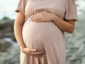 Kobieta w ciąży, która zastanawia się nad stosowaniem retinolu, delikatnie obejmuje swój brzuszek.