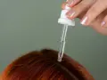 Dłoń z pipetką aplikuje serum na rudą skórę głowy. Idealne rozwiązanie, czym nawilżyć skórę głowy.