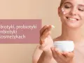 Uśmiechnięta kobieta aplikuje krem z prebiotykami na twarz. Pielęgnacja skóry z wykorzystaniem dobroczynnych składników.