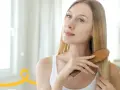 Kobieta szczotkuje długie blond włosy, przygotowując się do domowego peelingu skóry głowy.