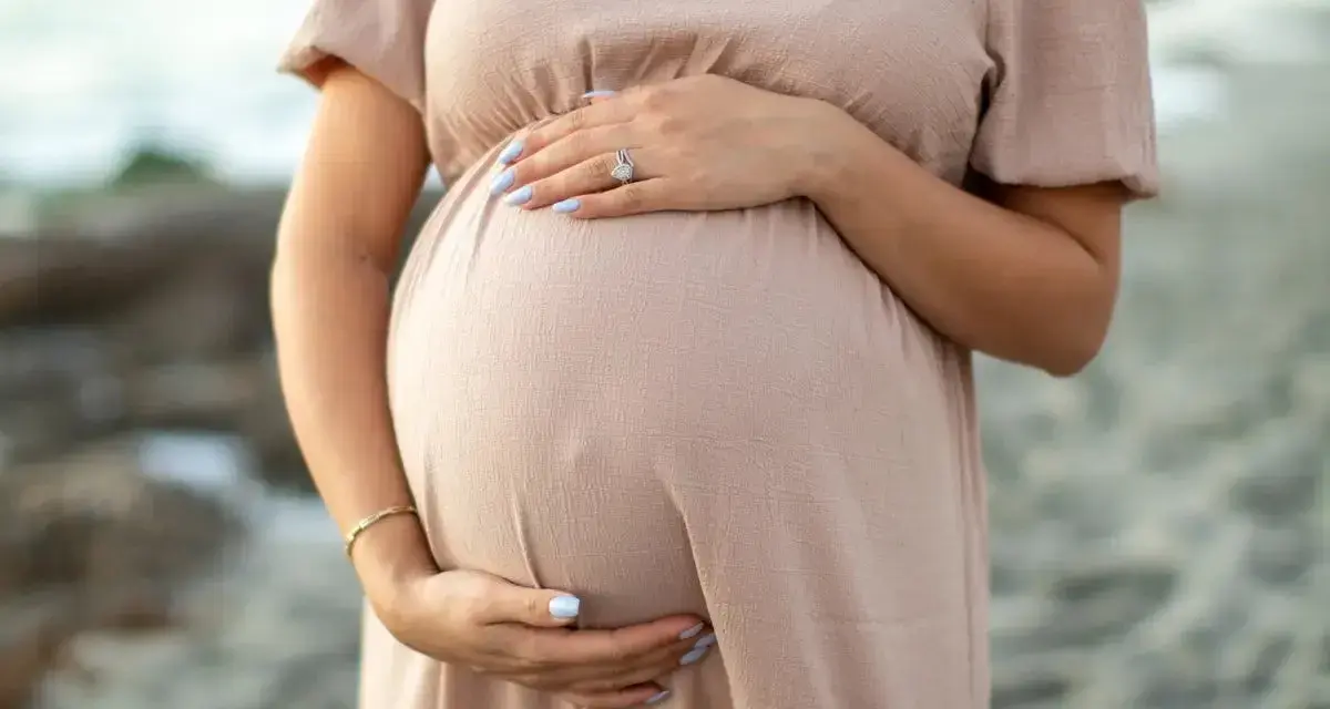 Kobieta w ciąży, która zastanawia się nad stosowaniem retinolu, delikatnie obejmuje swój brzuszek.