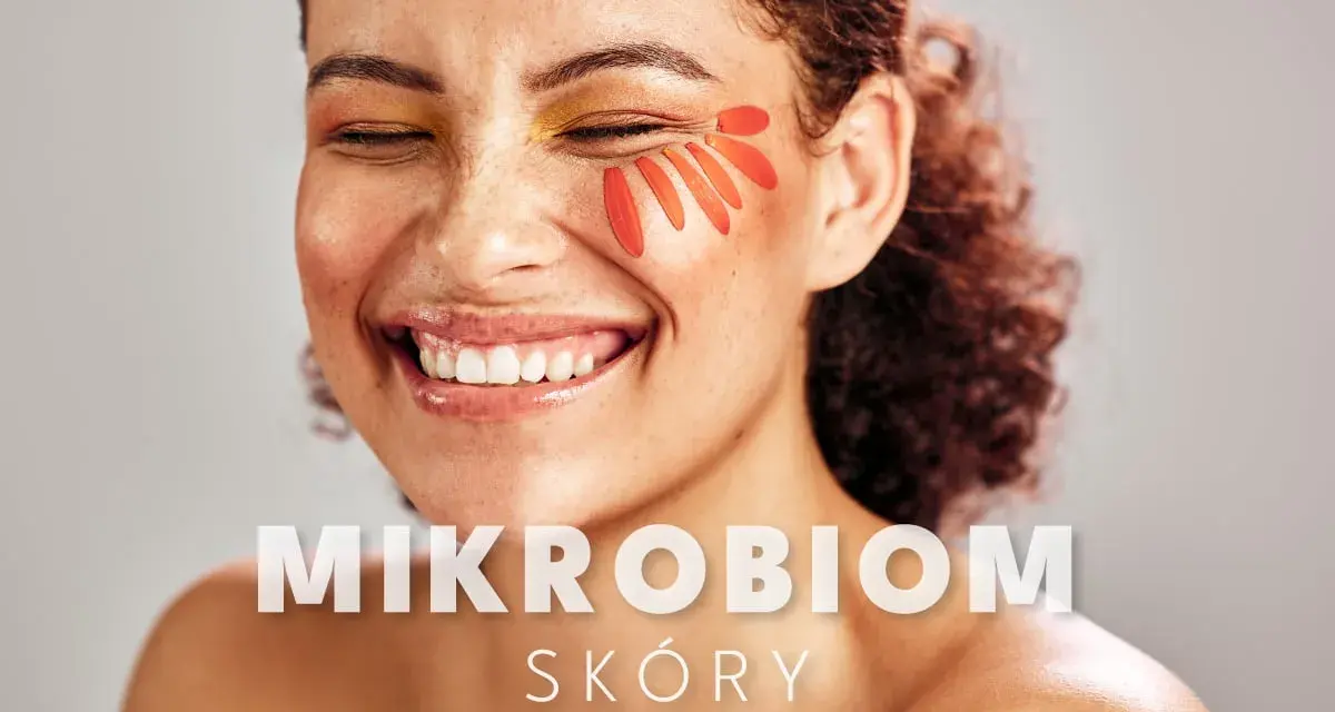 Uśmiechnięta kobieta z płatkami kwiatów na policzku. Tekst: "MIKROBIOM SKÓRY".