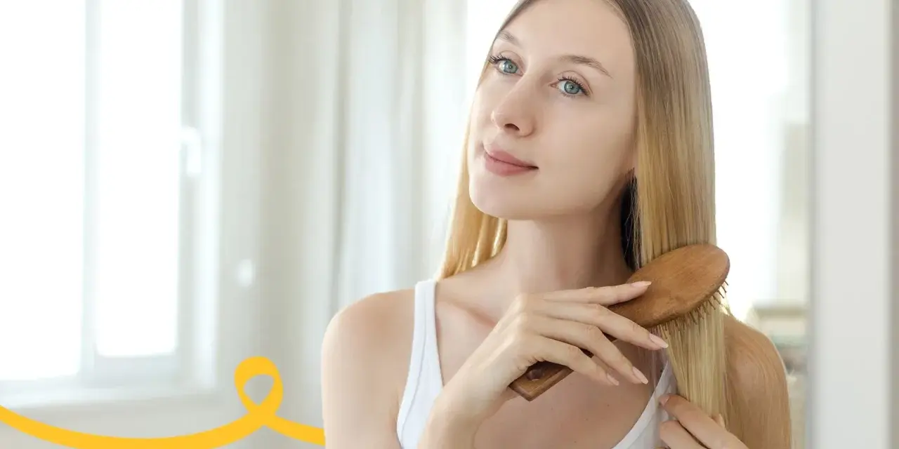 Kobieta szczotkuje długie blond włosy, przygotowując się do domowego peelingu skóry głowy.