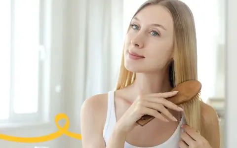 Kobieta szczotkuje długie blond włosy, przygotowując się do domowego peelingu skóry głowy.