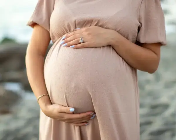 Kobieta w ciąży, która zastanawia się nad stosowaniem retinolu, delikatnie obejmuje swój brzuszek.