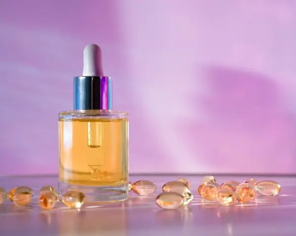 Serum z retinolem i kapsułki z retinalem na fioletowym tle.