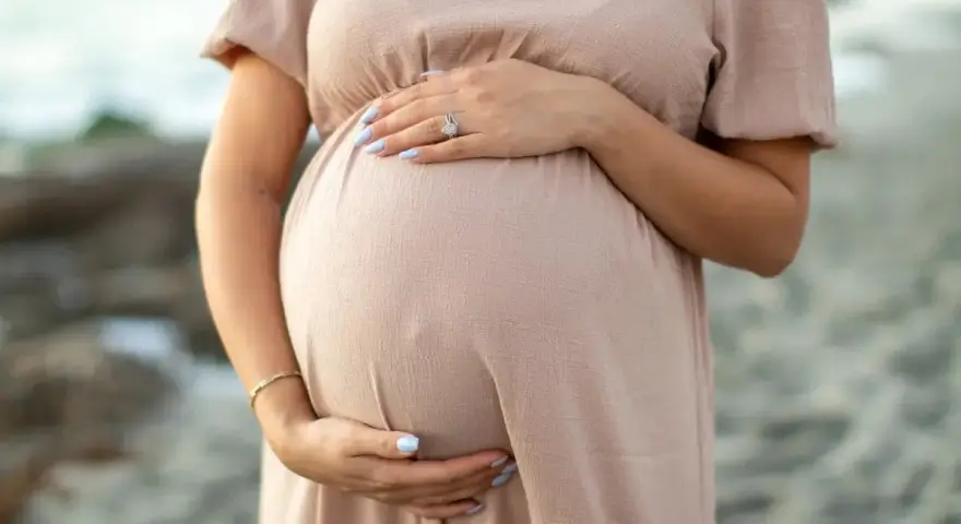 Kobieta w ciąży, która zastanawia się nad stosowaniem retinolu, delikatnie obejmuje swój brzuszek.