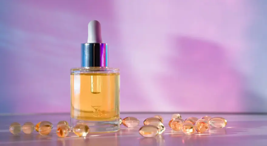 Serum z retinolem i kapsułki z retinalem na fioletowym tle.