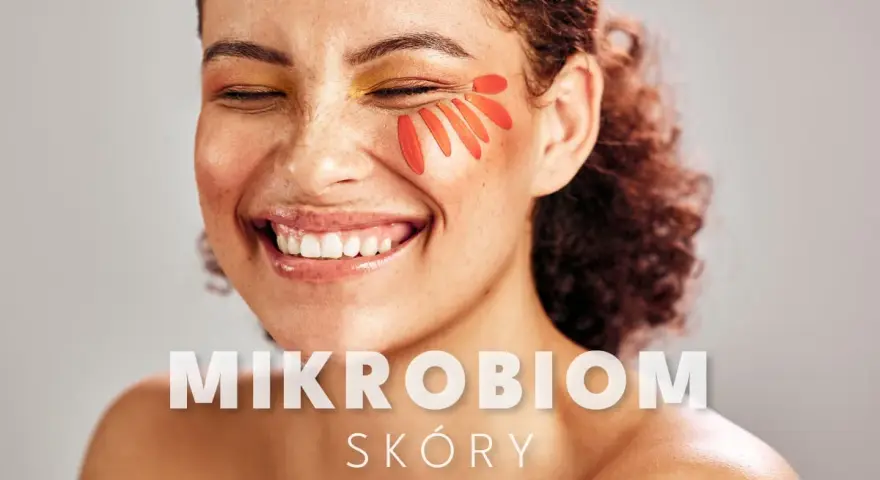 Uśmiechnięta kobieta z płatkami kwiatów na policzku. Tekst: "MIKROBIOM SKÓRY".
